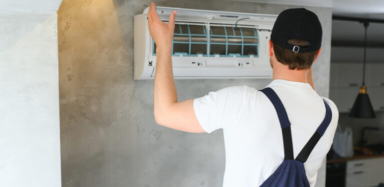 HVAC technician mounting a modern split air conditioner wall unit designed for eco-friendly refrigerants.