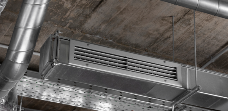 Suspended metal ductwork with air supply louvers and ventilation piping under an industrial concrete ceiling, showcasing AC service Saskatoon solutions by ONE Mechanical.