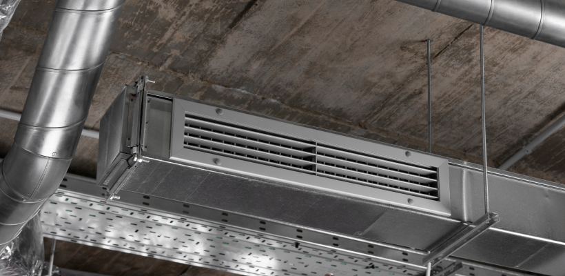 Suspended metal ductwork with air supply louvers and ventilation piping under an industrial concrete ceiling, showcasing AC service Saskatoon solutions by ONE Mechanical.