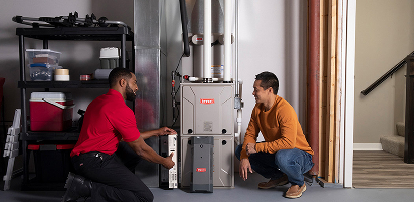 HVAC technician showing a homeowner a newly installed Bryant high-efficiency gas furnace during a furnace installation Saskatoon service